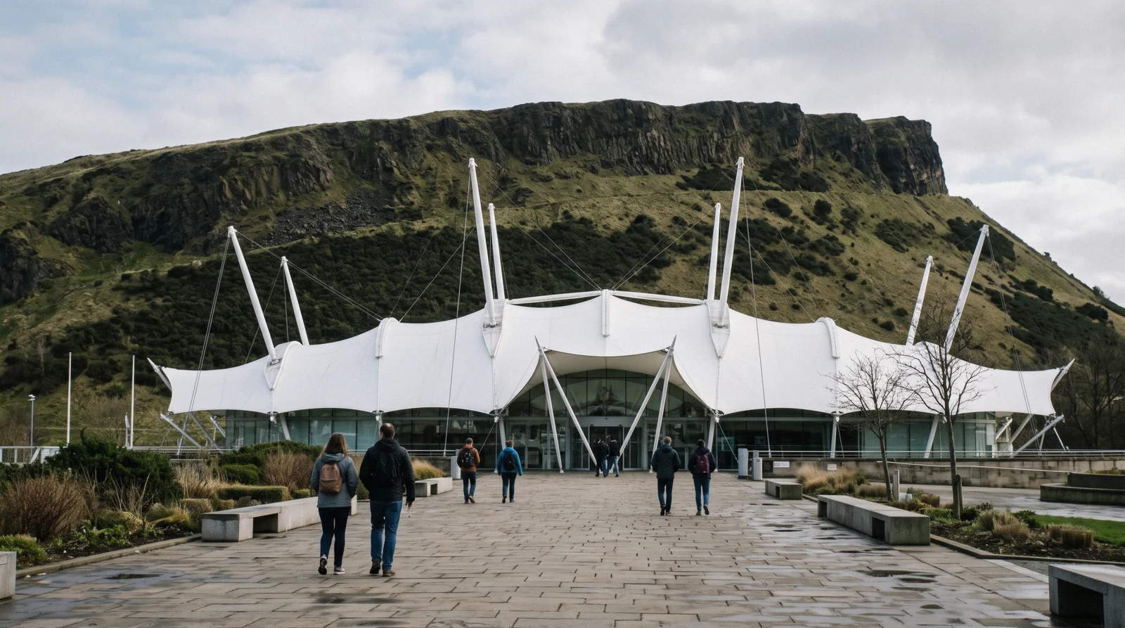 The white tented roof and glass frontage of Dynamic Earth on Holyrood Road in Edinburgh, with the Salisbury Crags rising behind it