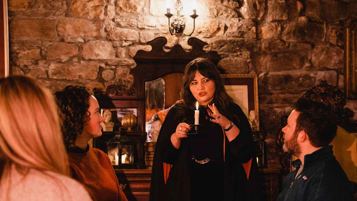 Storyteller with a lantern in the Blair Street Underground Vaults on an evening ghost tour with whisky in Edinburgh