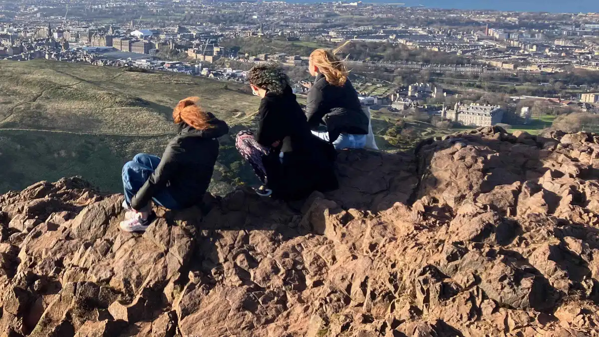 Walkers above the monuments of Calton Hill with Arthur's Seat behind on a guided Edinburgh hill hike